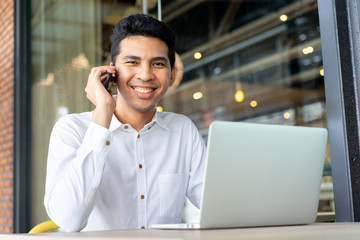 close up malaysian businessman talking business with partner and using laptop at outside office , lifestyle concept