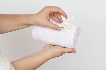 towel and white starfish in female hands, concept of massage, spa, on a light background, copy space