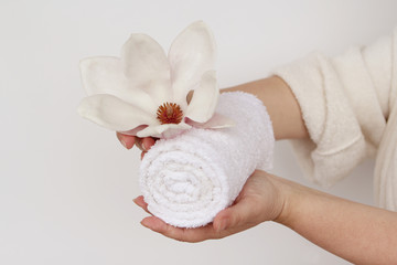 towel and flower in female hands, concept of massage, spa, on a light background, copy space