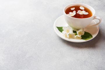 Cup of tea with Jasmine flowers on a gray table with copy space.