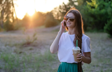 A young girl with a coffee cocktail. In sunglasses. Summer image.