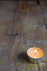 Obraz na płótnie Canvas Top view of a candle on worn wooden table in vertical with copy space
