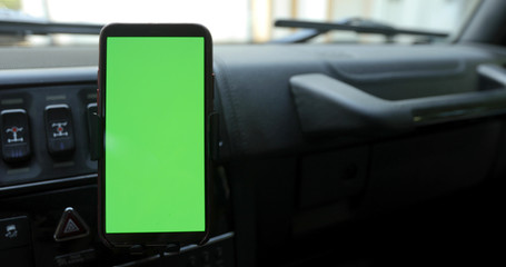 Smartphone with a green screen in the holder on the windshield