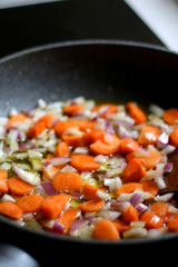 Roasting carrot and onion on olive oil. Selective focus.