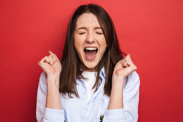 Surprised emotional young beautiful woman posing isolated over red wall background.