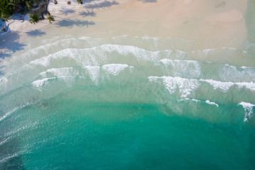 Aerial top view of ocean waves, beach and rocky coastline and beautiful forest. Beautiful nature background.