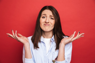 Amazing confused young beautiful woman posing isolated over red wall background.