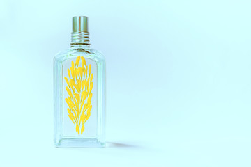 Transparent perfume bottle on a blue background decorated with yellow flower petals