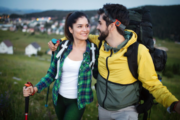 Backpackers couple hiking during fall with sticks