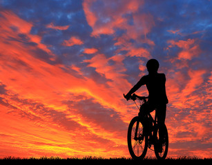 Obraz premium Silhouette man and bike relaxing on blurry sunrise sky background.
