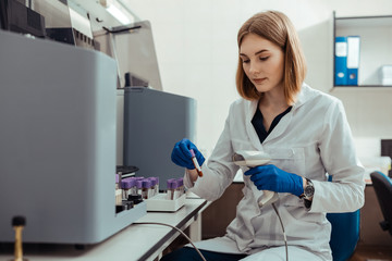 Professional female lab worker holding a test tube with blood