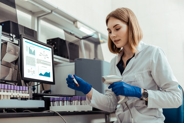 Smart blonde woman holding a test tube with blood