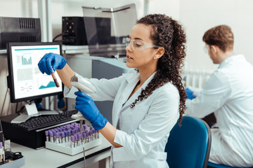 Intelligent young woman scanning the test tube