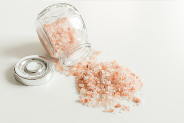 Pink sea salt on white background. Hip of red himalaya salt on white.