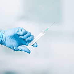 Close up of doctor's hand in medical gloves with a syringe