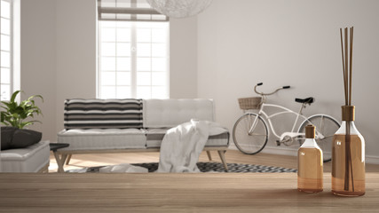 Wooden table top or shelf with aromatic sticks bottles over blurred modern scandinavian minimalist living room with big carpet, white architecture interior design