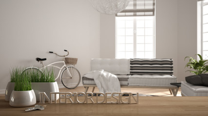 Fototapeta na wymiar Wooden table, desk or shelf with potted grass plant, house keys and 3D letters making the words interior design, over blurred modern living room, project concept copy space background