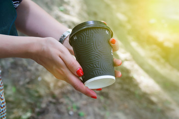 Female hand with black paper cup of coffee take away