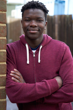 Portrait Of Smiling Teenage Boy Leaning Against Wall In Urban Setting