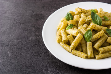 Penne pasta with pesto sauce on black background. Copy space