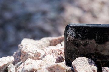 Broken glass of smartphone on gravel granite stones. Selective focus