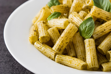 Penne pasta with pesto sauce on black background. Close up