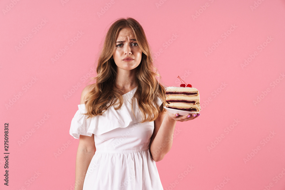 Canvas Prints Image of caucasian sad woman wearing white dress looking at camera and holding piece of cake