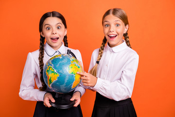 Fototapeta premium Portrait of two person nice attractive lovely charming cute cheerful cheery amazed funny pre-teen girls finding map new route destination isolated over bright vivid shine orange background