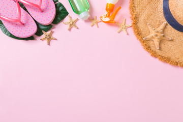 Beach accessories with straw hat, sunscreen bottle and seastar on pink background top view with copy space