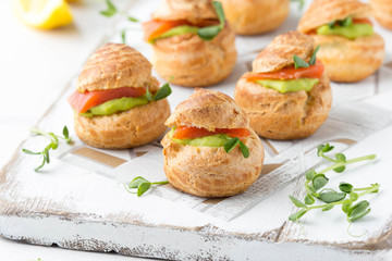 Snack cakes profiteroles with green pea cream and salmon red fish. Exquisite appetizer, tasty lunch, traditional food