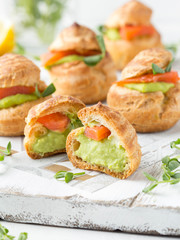 Snack cakes profiteroles with green pea cream and salmon red fish. Exquisite appetizer, tasty lunch, traditional food