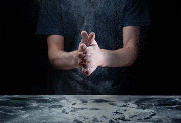 Obraz na płótnie Canvas hand clap and white flour on black background