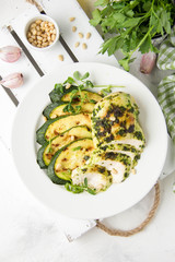 Grilled chicken fillet with green herb marinade, with slices of fried zucchini and pine nuts, healthy lunch