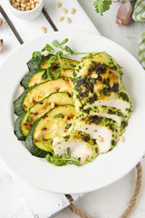 Grilled chicken fillet with green herb marinade, with slices of fried zucchini and pine nuts, healthy lunch