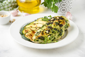 Grilled chicken fillet with green herb marinade, with slices of fried zucchini and pine nuts, healthy lunch