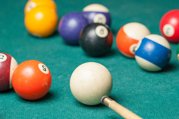 Billiard balls and a stick on a green table. Billiard balls isolated on a green background