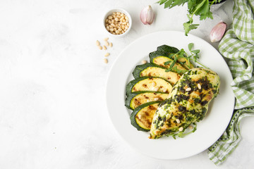 Grilled chicken fillet with green herb marinade, with slices of fried zucchini and pine nuts, healthy lunch