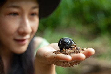 Go out to experience nature . Snail from natural water on the hand of a woman at Rivers, streams .
