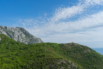 Mountains in the Balkans mountains. Green cliff with forest and clouds in the sky. Adriatic sea in Montenegro. Tropical view