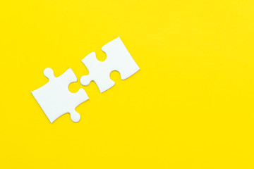 2 jigsaw puzzle on solid yellow background using as 2 important thing combine or working together...