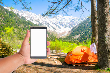 hand hold mobile phone on tent with a view of japan alps mountain, Japan