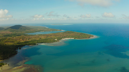 Tropical island Balabac covered with green rain forest against the blue sky with clouds and blue sea from above. Seascape: Ocean and sky. Palawan, Philippines