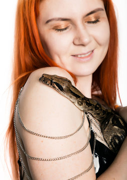 sexy redhead woman holding snake. close-up photo girl with pygmy python on a white background