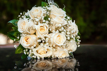 bouquet of cream roses on the hood of a black car