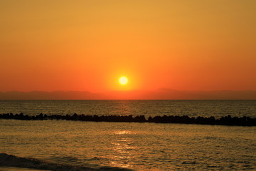Fototapeta na wymiar 新潟の日本海に沈む夕日と佐渡島の島影