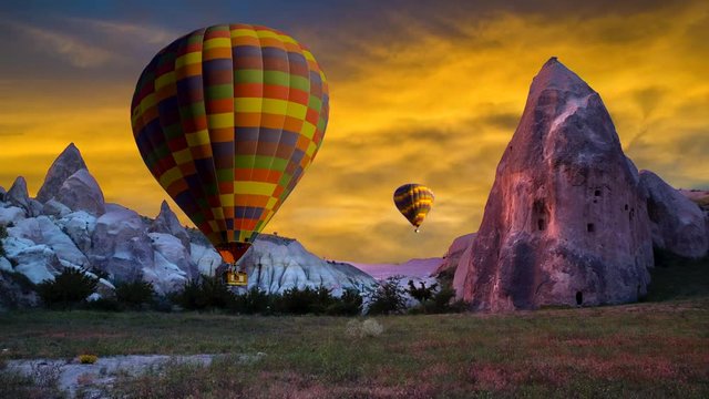 Cinemagraph of fairy chimney in Cappadocia, Turkey, with balloons set sunset sky colors and cloud motion.