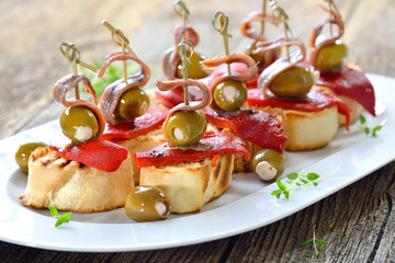 Spanische Tapas: Gegrilltes Baguette mit geröstetem und eingelegtem Paprika, gefüllten Oliven und...