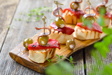 Spanische Tapas: Gegrilltes Baguette mit geröstetem und eingelegtem Paprika, gefüllten Oliven und...