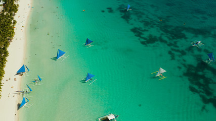 Fototapeta na wymiar Tropical white sand beach with sailing yachts, hotels near the blue lagoon and corall reef. aerial view, Boracay, Philippines. Seascape with beach on tropical island. Summer and travel vacation