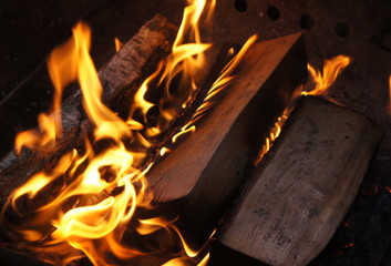 Firewood burns close up at night.